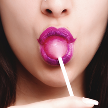 Load image into Gallery viewer, Woman savors a pink lollipop with vibrant purple lipstick. 


